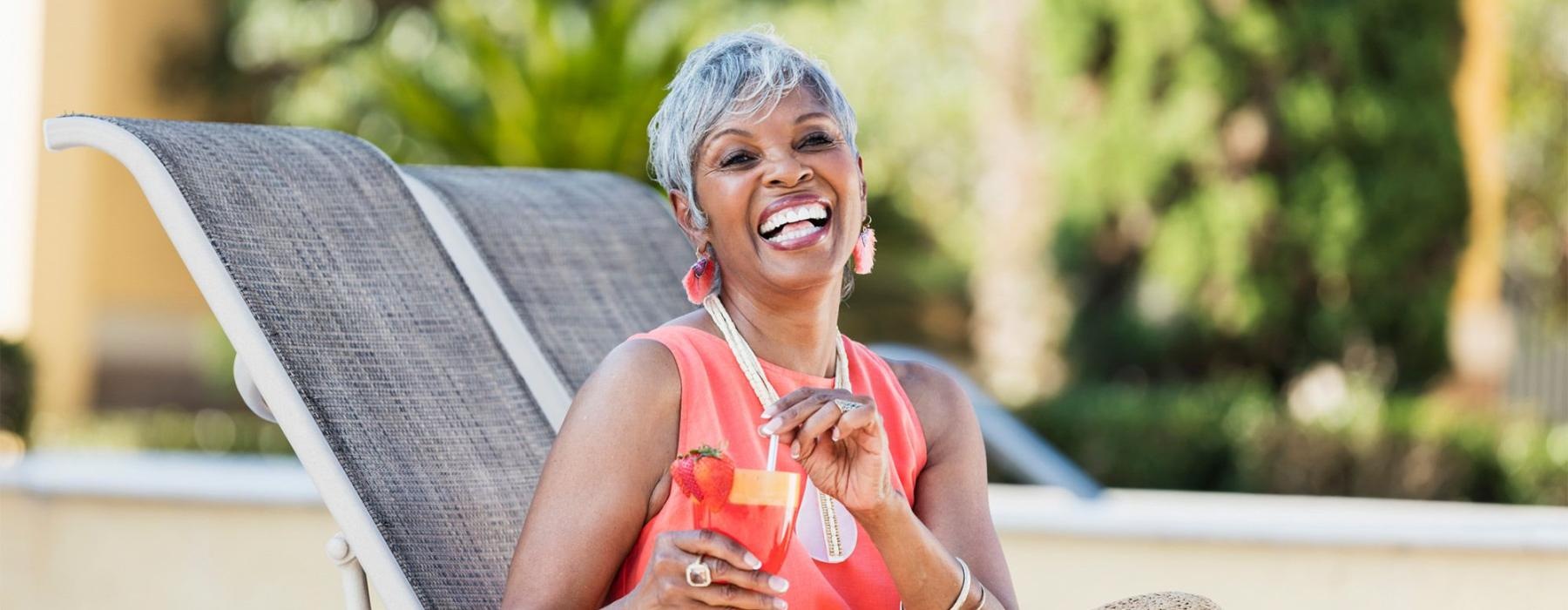 a woman sitting on a chair outside with a drink in her hand